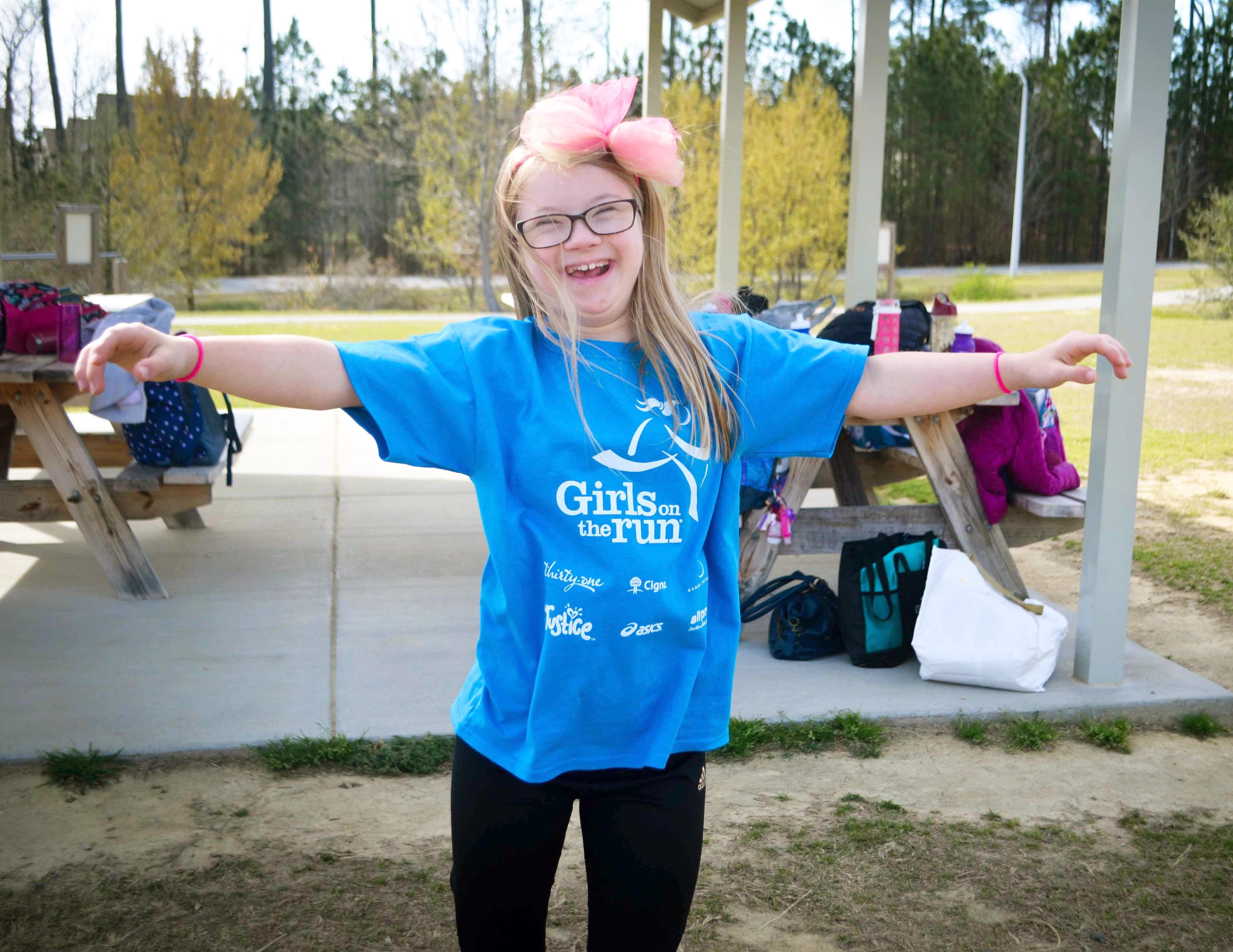 Girls on the Run participant smiles with arms wide